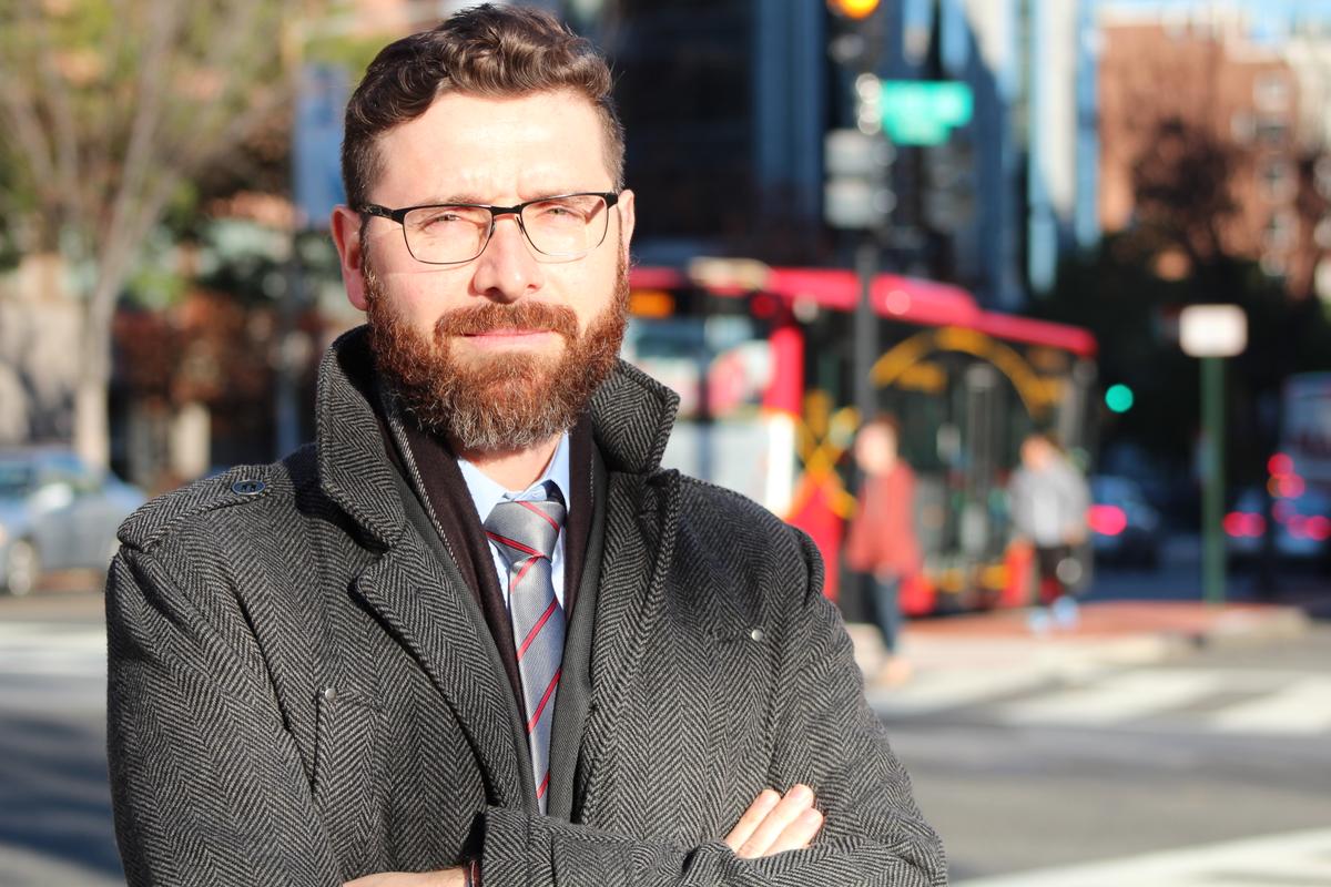 Photo of Francisco Posada with arms crossed in front of a blurred out background of a street.